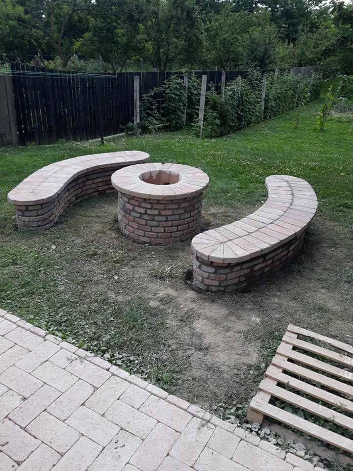 Két íves téglapad és középen kialakított kör alakú tűzrakóhely a kertben.